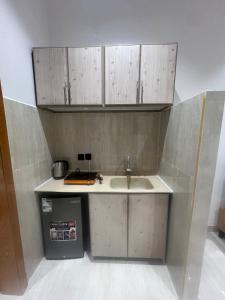 Una cocina con fregadero y armarios de madera. en Modern apartment with elegant design, en Dhahran