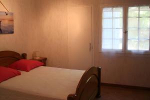 a bedroom with a bed with red pillows and a window at Le Mas Des Glycines in Les Vignères