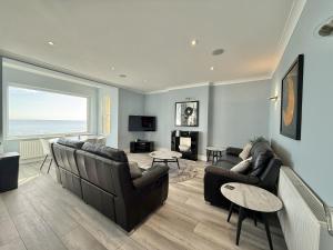 a living room with leather furniture and a large window at Sunnybeach in Seaton