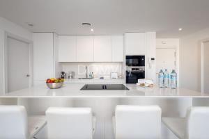 a white kitchen with white cabinets and a sink at Modern 2BD Apartment with Huge Terrace NaviGolf in Málaga