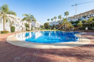 a large swimming pool in a courtyard with palm trees at Modern 2BD Apartment with Huge Terrace NaviGolf in Málaga