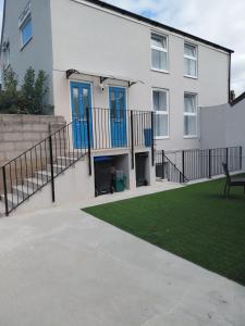 a white house with blue doors and a lawn at Blue Door Apartments in Dover