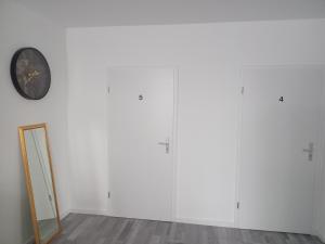 a room with white cabinets and a clock on the wall at Hostel Diana in Wermelskirchen