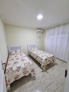 a bedroom with two beds and a window with curtains at Aconchego Paraíso 2 Shopping com Garagem e Suíte in São João del Rei