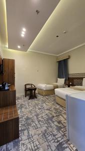 a hotel room with two beds and a table at فندق كنوز العنود مكة للغرف والأجنحة الفندقية - Knoz Al Anood Hotel Makkah For Hotel Rooms and Suites in Makkah +37 photos