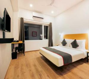 une chambre avec un lit, un bureau et une télévision dans l'établissement Townhouse Rajahmundry City Centre Formerly Svas Inn, à Godāvari