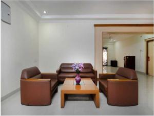 a living room with couches and a vase of flowers on a table at Townhouse Rajahmundry City Centre Formerly Svas Inn in Godāvari
