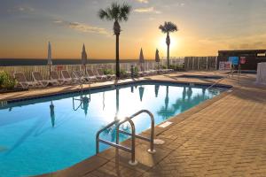 a large swimming pool with chairs and palm trees at Luxury 2BR Beachfront Condo - Panama City Beach in Panama City Beach