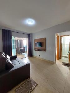 ein Wohnzimmer mit einem schwarzen Sofa und einem TV in der Unterkunft Flat - Fiore Prime Flat Style - 5 pessoas - Apartamento - 5 andar in Caldas Novas