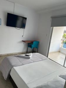 a bedroom with a bed and a tv on the wall at Hotel Maria del Mar planeta Rica in Planeta Rica