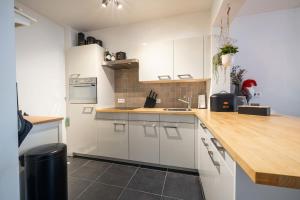 een keuken met witte kasten en een houten aanrechtblad bij JoLi Beach Apartment in Middelkerke +1 foto