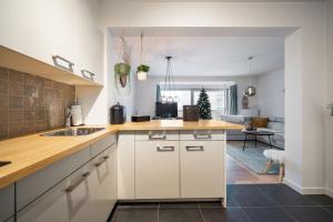 een keuken met witte kasten en een woonkamer bij JoLi Beach Apartment in Middelkerke