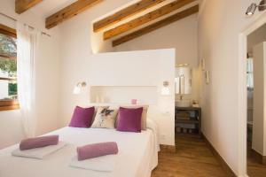 Un dormitorio con una cama blanca con almohadas moradas. en Garbo by Vintage Travel, en Cala Morell