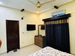 a bedroom with a bed and a dresser and a television at Crest View Guest House Islamabad in Islamabad