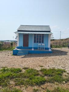 une petite maison bleue avec une chaise dans un champ dans l'établissement DADA TOURIST COTTAGE & Camping site, à Cherrapunji 16 autres photos