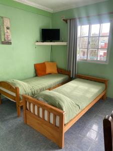 zwei Betten in einem Zimmer mit grünen Wänden in der Unterkunft Complejo Gago DTO 1 in Puerto Madryn