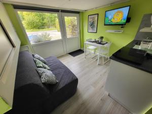 a room with a couch and a table and a television at L'Echappée verte in Spa
