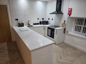 a kitchen with white counters and a counter top at Liverpool Penthouse - Sleeps 8 - City Centre in Liverpool +5 photos