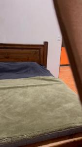 a bed with a green blanket on top of it at Cabaña vista al vall in Paraíso