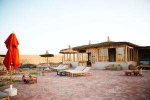 a patio with couches and umbrellas in the desert at Les Bedouins Agafay in Oulad Akkou