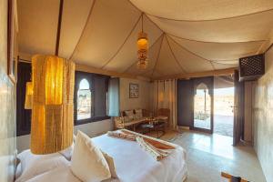 a bedroom with a bed in a room with windows at Les Bedouins Agafay in Oulad Akkou