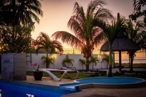 a resort with a pool and palm trees and a sunset at Stella Marris beachfront villa in Pointe aux Sable