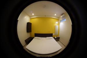 Habitación pequeña con cama y pared amarilla en Vitthal Inn, en Pandharpur