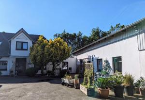 a white house with potted plants in front of it at Ferienwohnungen-im-Koog in Wesselburenerkoog