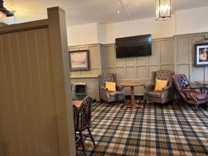 a waiting room with chairs and a table and a flat screen tv at The vale of york in Thirsk