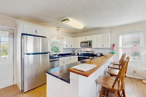 a kitchen with white cabinets and a stainless steel refrigerator at No Regrets Down in Emerald Isle