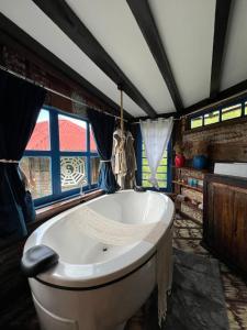 a large white tub in a room with windows at CABANA OCTAGONAL c BANHEIRA in Urubici