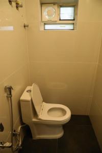 a white toilet in a bathroom with a window at T Nagar 1BHK Studio Shopping Cntrl - G3 Tulsi in Chennai +1 photo