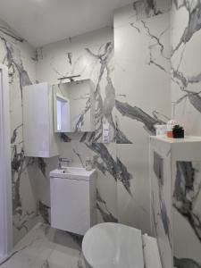 a bathroom with a white toilet and a marble wall at Niepodległości Park View Studio by BookingHost in Kraśnik