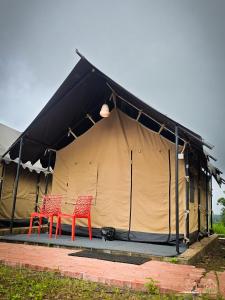 two red chairs sitting in front of a tent at Huts And Hunters Resort Saputara in Saputara
