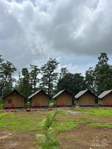 a row of houses with red chairs in a field at Huts And Hunters Resort Saputara in Saputara