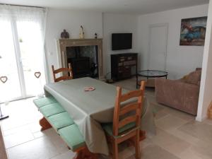 a living room with a table and chairs and a couch at Petite maison de campagne avec poêle à bois, 20 mn des plages in Bréhand