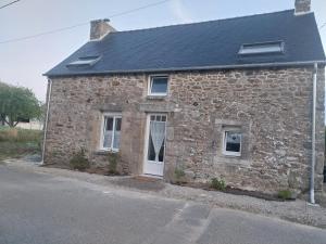an old stone house with a white door at Petite maison de campagne avec poêle à bois, 20 mn des plages in Bréhand