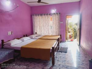 a bedroom with two beds and a pink wall at Golden Rich in Gokarna
