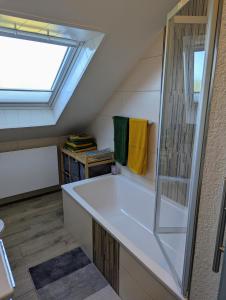 Baño en el ático con bañera y ventana en Ferienwohnung am Maarberg, en Ulmen 18 fotos más