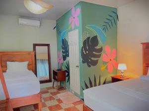 a bedroom with two beds and a mural of flowers at Hostal Edén in Moyogalpa