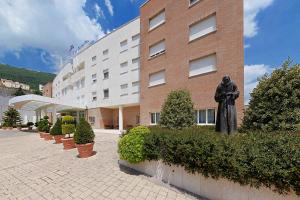 una estatua de un hombre parado frente a un edificio en Hotel Centro di Spiritualità Padre Pio en San Giovanni Rotondo