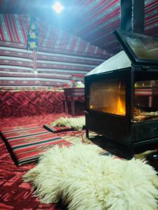 a living room with a fireplace and a white rug at Sunrise Magic Camp in Wadi Rum