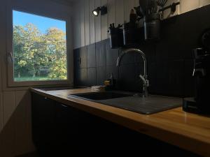 Una encimera de cocina con un fregadero y una ventana. en Beaux-Regards, en Saint Lo