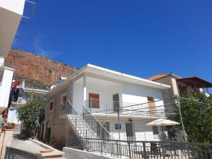 a white house with stairs and an umbrella at The olive House in Leonidio