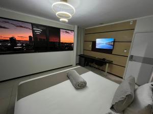 a living room with a white bed and a television at Águas Palace Hotel in Petrolina