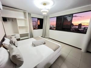 ペトロリーナにあるÁguas Palace Hotelの白いベッドと大きな窓のある寝室