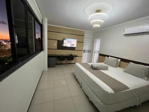 a bedroom with a large bed and a flat screen tv at Águas Palace Hotel in Petrolina