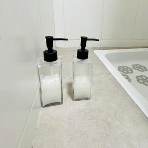 two glass bottles sitting on the floor next to a bath tub at Studio Conexión Mendoza moderno céntrico Wifi alta velocidad y a pasos del Parque Gral San Martín y Aristides Villanueva in Godoy Cruz