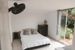 a white bedroom with a bed and a window at APARTAMENTO CAMPESTRE EN EJE CAFETERO in Manizales