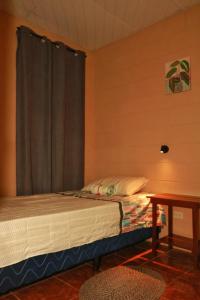 1 dormitorio con 1 cama con cortina y mesa en Las Palmeritas, en Ahuachapán